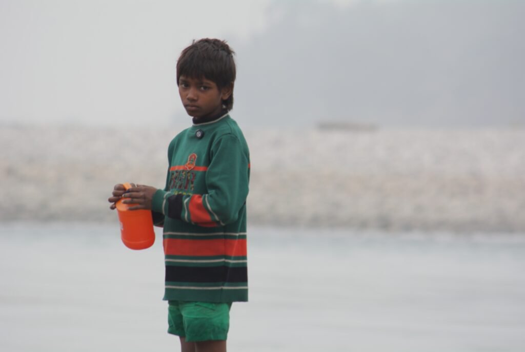 A 13 year old brown kid looking at the camera with a plastic container in his hands.